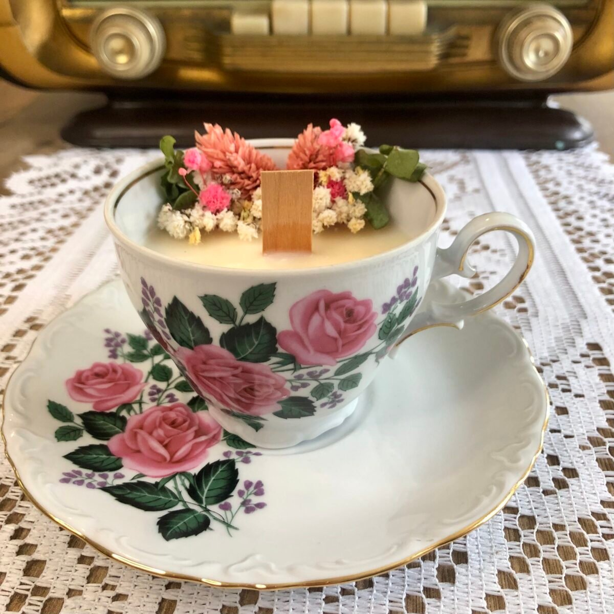Bougie vintage dans une jolie et poétique tasse à thé avec sa soucoupe blanche et rose avec des fleurs séchées dans les tons roses