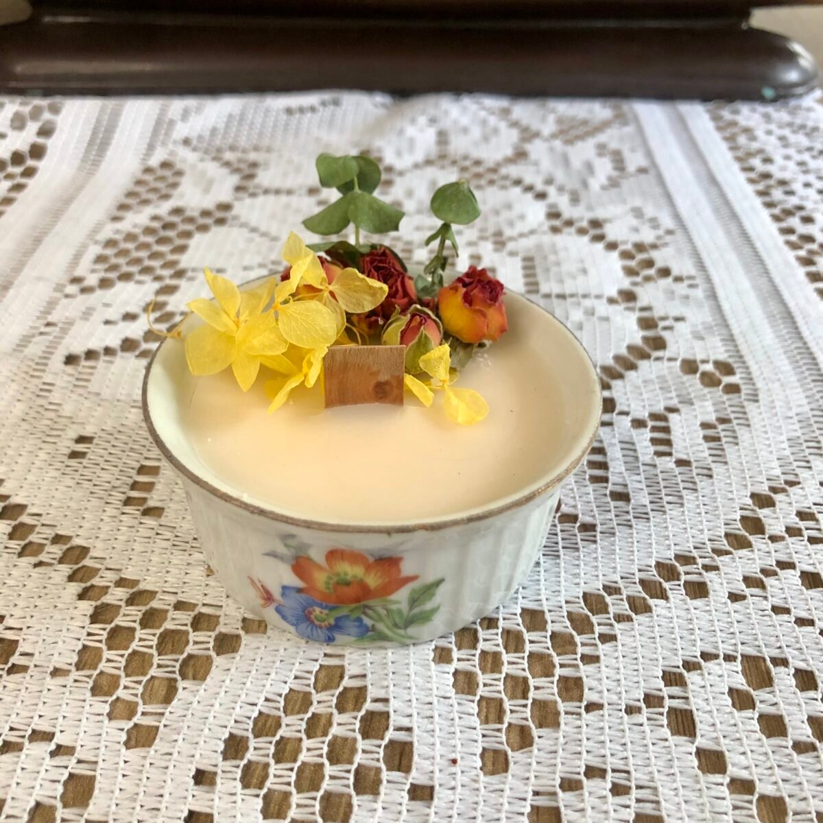 Bougie artisanale dans un tout petit pot en céramique vintage et colorée avec des fleurs séchées colorées dans les tons jaunes et oranges