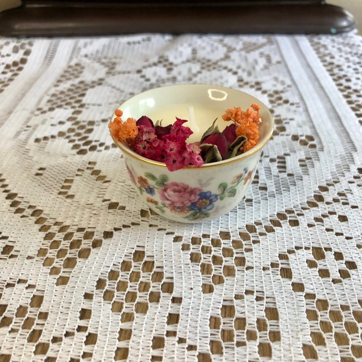 Bougie artisanale dans un tout petit pot en céramique vintage et colorée avec des fleurs séchées colorées