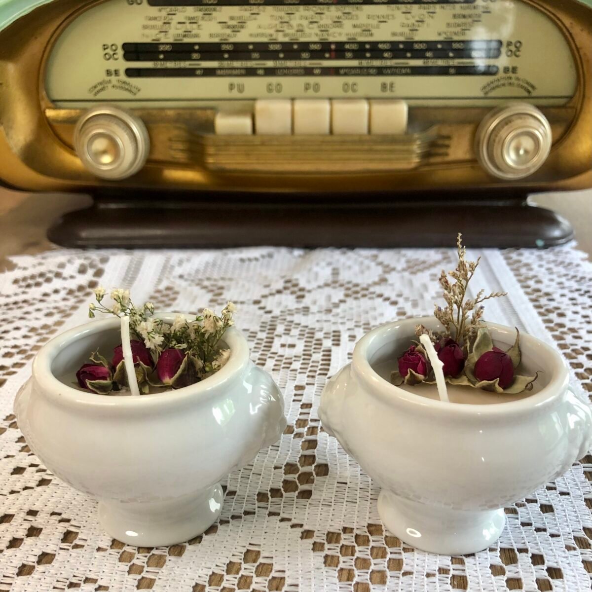 Deux bougies artisanales dans des petits pots en céramique blancs vintage avec roses séchées