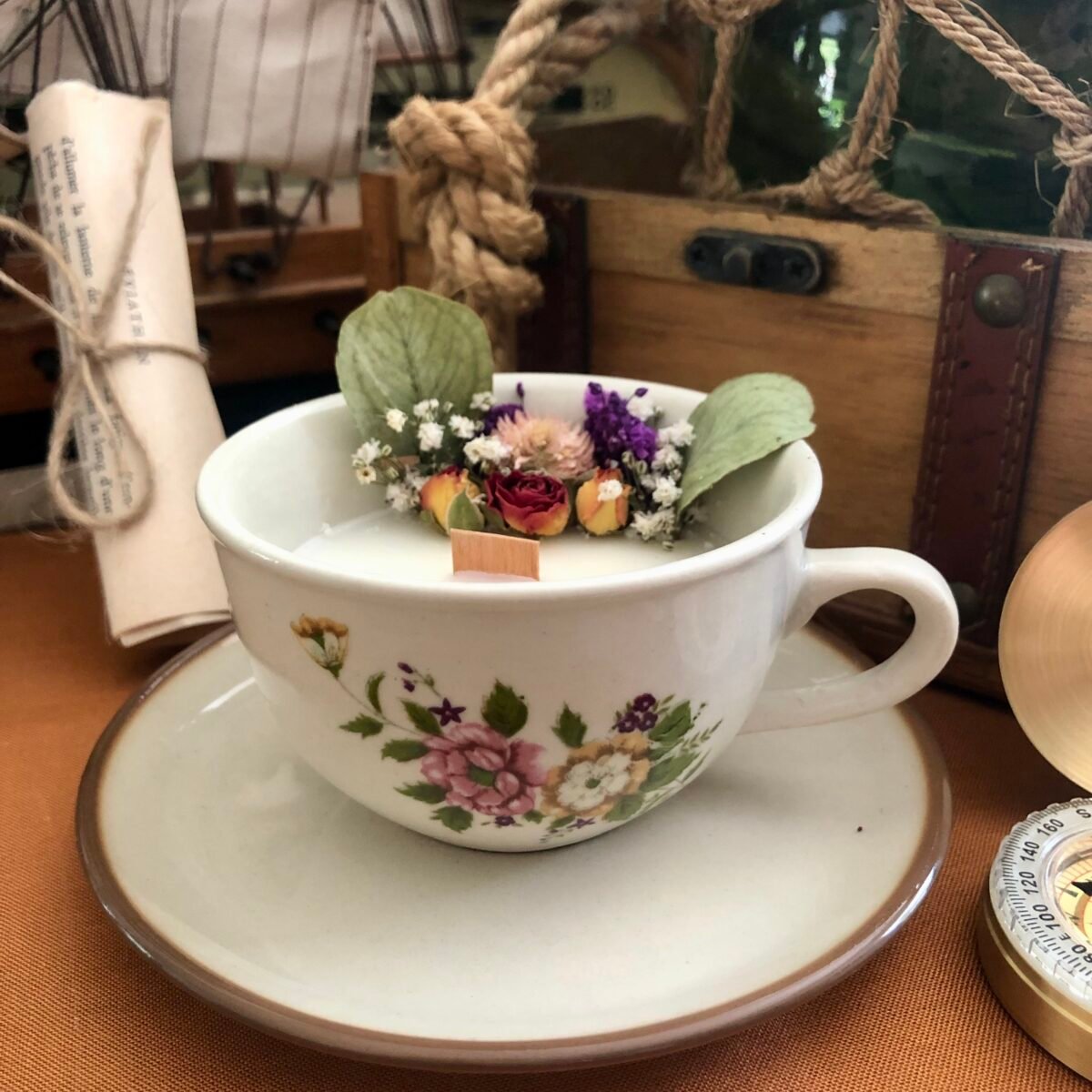 Bougie artisanale dans une tasse à café avec fleurs séchées colorées et eucalyptus