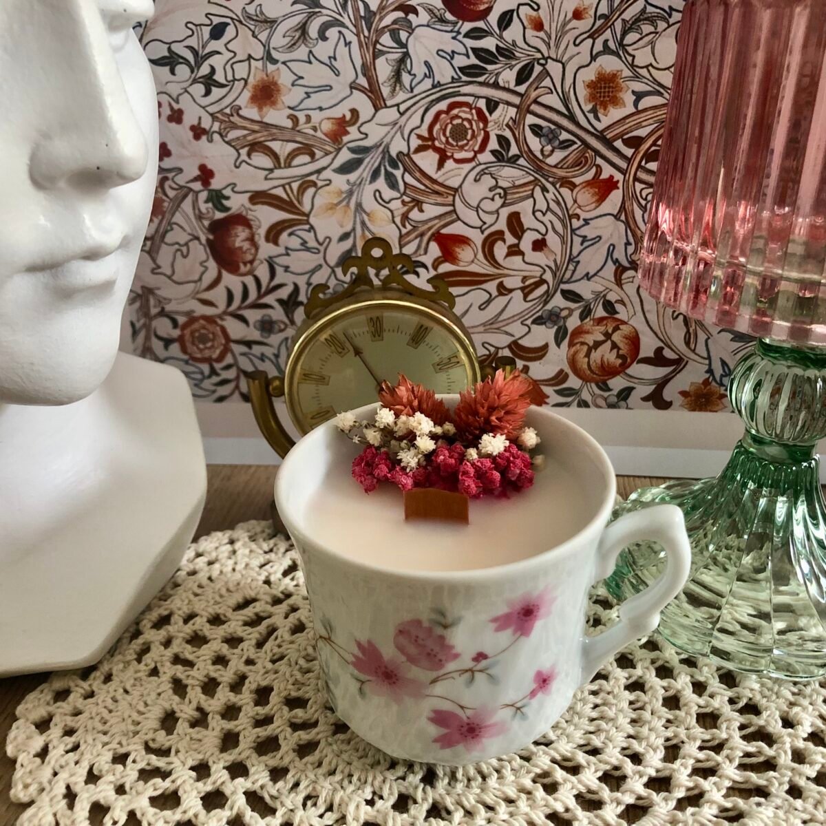 Bougie artisanale dans une petite tasse à café vintage dans les tons roses et blancs avec des fleurs séchées