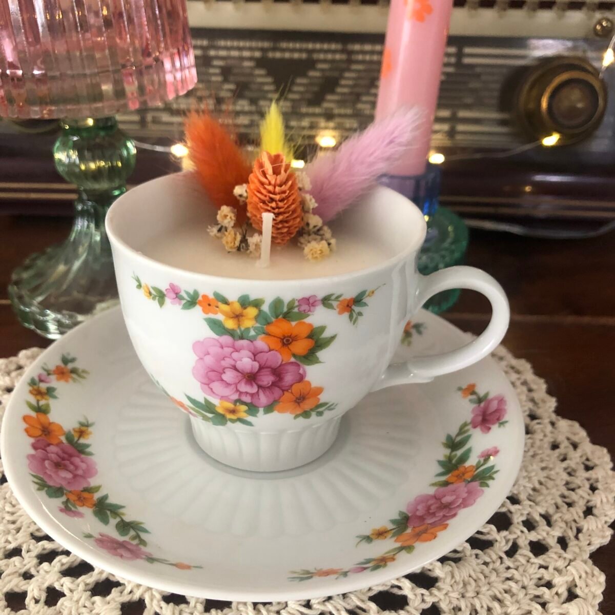 Bougie dans une tasse à fleurs colorées avec soucoupe et fleurs séchées