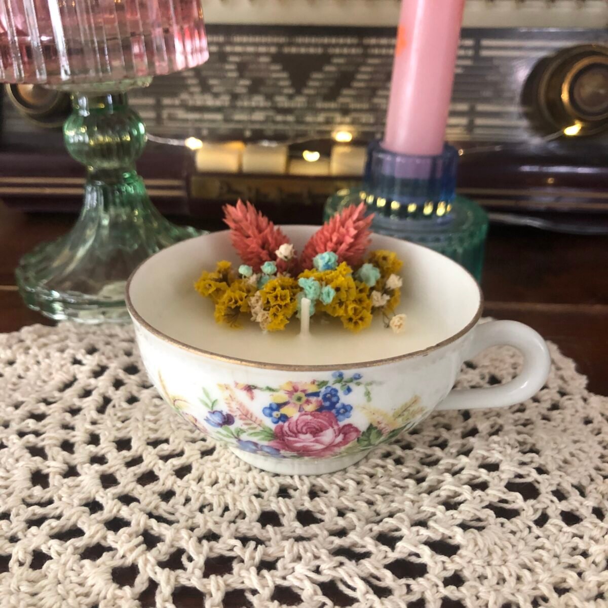 Bougie artisanale dans une tasse à thé blanche vintage et élégante avec des fleurs séchées colorées